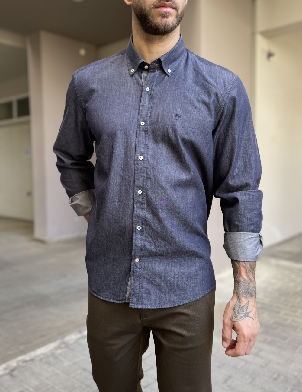 Ανδρικό πουκάμισο με denim όψη που διαθέτει γιακά κολάρο, κλείσιμο με κουμπιά, έχει ανάγλυφο σχέδιο με το λογότυπο της εταιρείας πάνω στην τσέπη του στήθους.